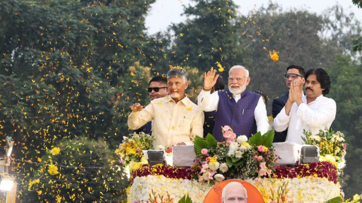 Chandrababu Naidu, Narendra Modi and Pawan Kalyan wave and greet the crowd from a flower-decked open vehicle as petals fall around them.