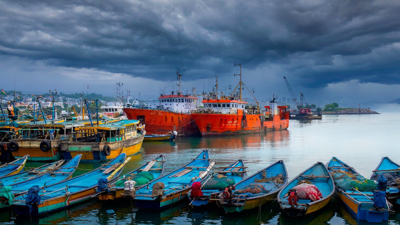Fishing boats moored at Visakhapatnam fishing harbour under dark storm clouds