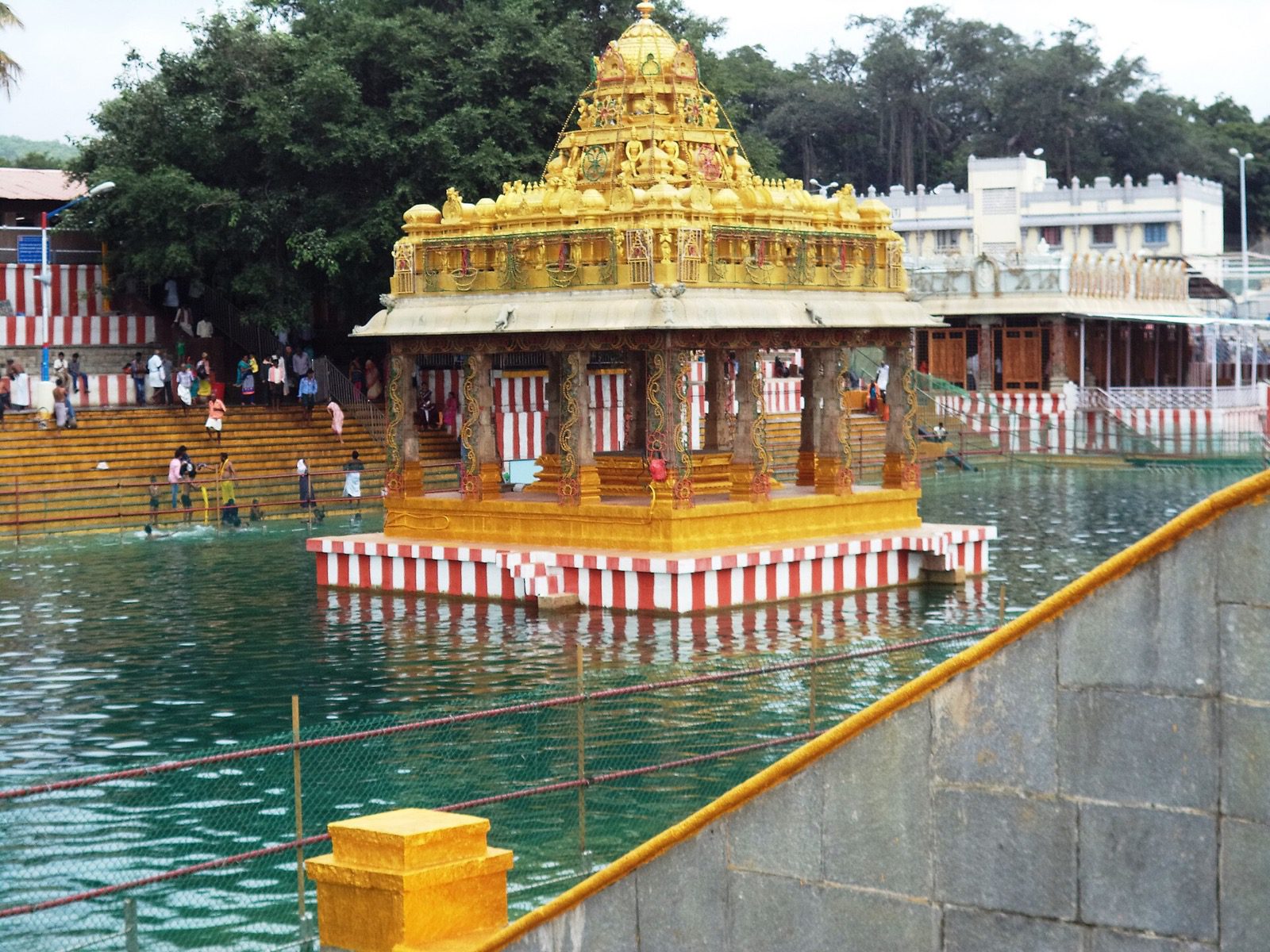 The gilded mandapam in the middle of Swami Pushkarini at Tirumala, with devotees on the steps of the tank.
