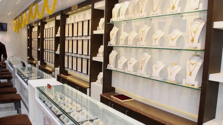Gold necklaces on display stands and bangles in glass counters at a jewellery shop decorated with marigold garlands.
