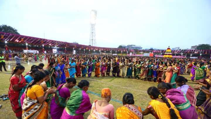 Women playing Bathukamma around a tall flower stack, representative image