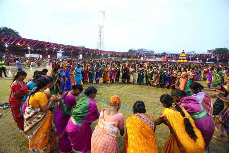 Women playing Bathukamma around a tall flower stack, representative image