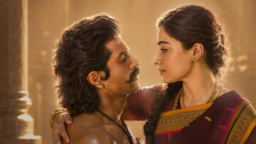 Vijay Deverakonda and Rashmika Mandanna, in period costume, face each other in a film still.