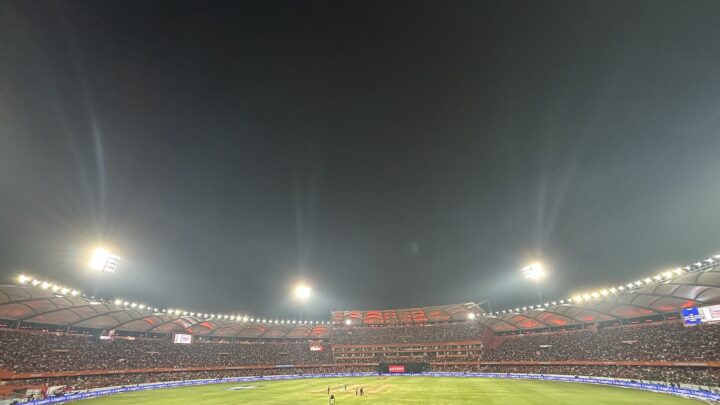 A packed, floodlit cricket stadium in Hyderabad during a night match.