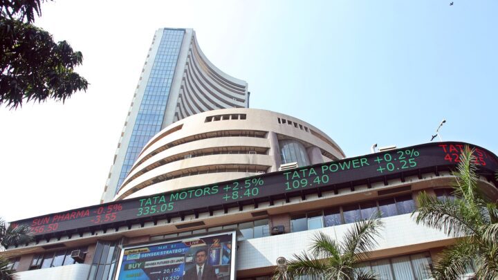 The curved BSE tower and the electronic share-price ticker on its Dalal Street building in Mumbai, seen from street level.