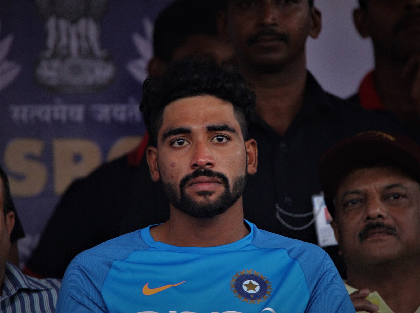 Mohammed Siraj, wearing an India team shirt, seated among other people.
