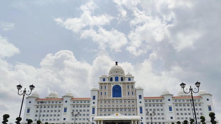 Front view of the white domed Telangana State Secretariat building in Hyderabad under a cloudy sky
