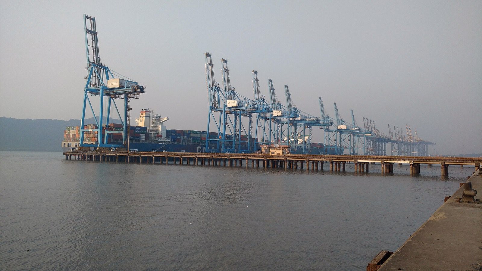 Container cranes and a docked container ship at Jawaharlal Nehru Port in Navi Mumbai.