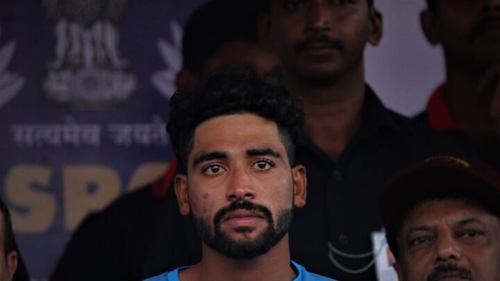 Mohammed Siraj, wearing an India team shirt, seated among other people.